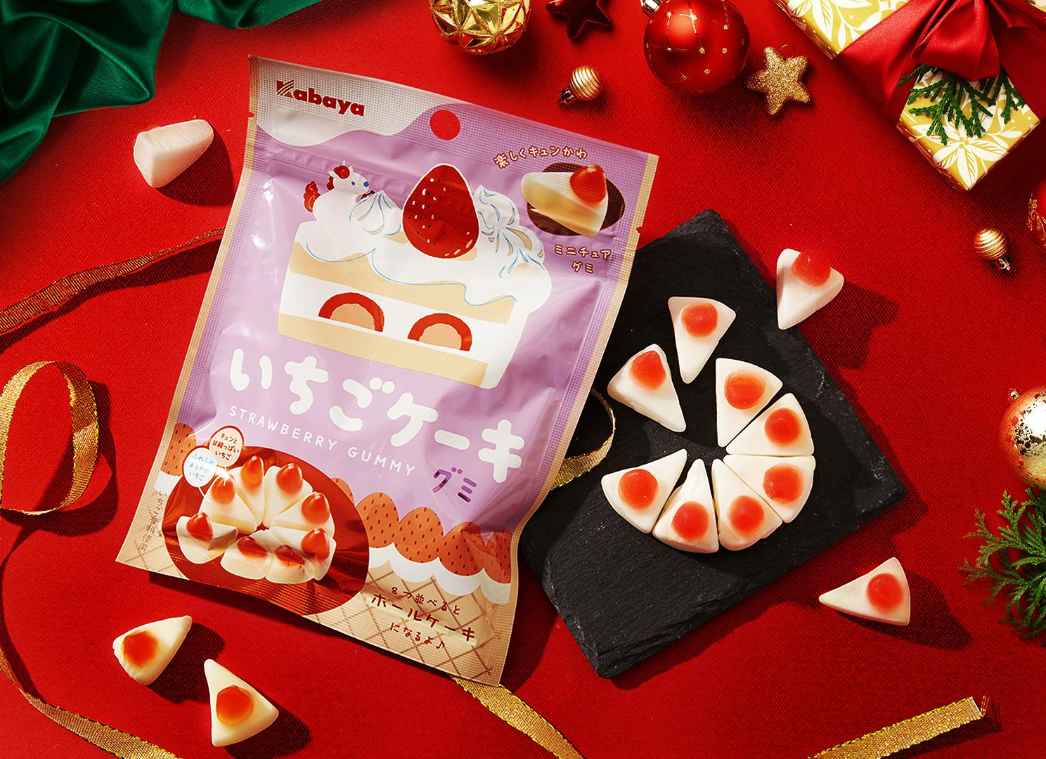 Christmas Cake Gummies sit against a holiday backdrop, surrounded by Christmas green & red colors plus other holiday motifs.