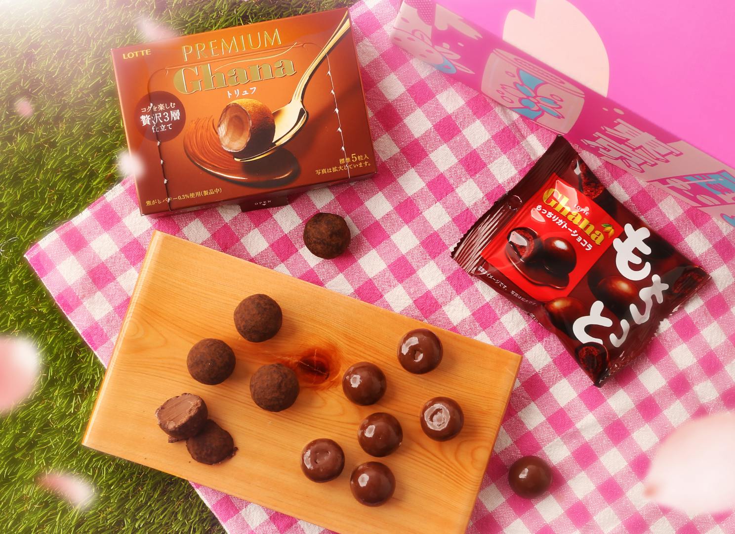 Chocolate truffle and bite-sized cake is displayed on a cutting board under cherry blossoms Chocolate truffle and bite-sized cake is displayed on a cutting board under cherry blossoms
