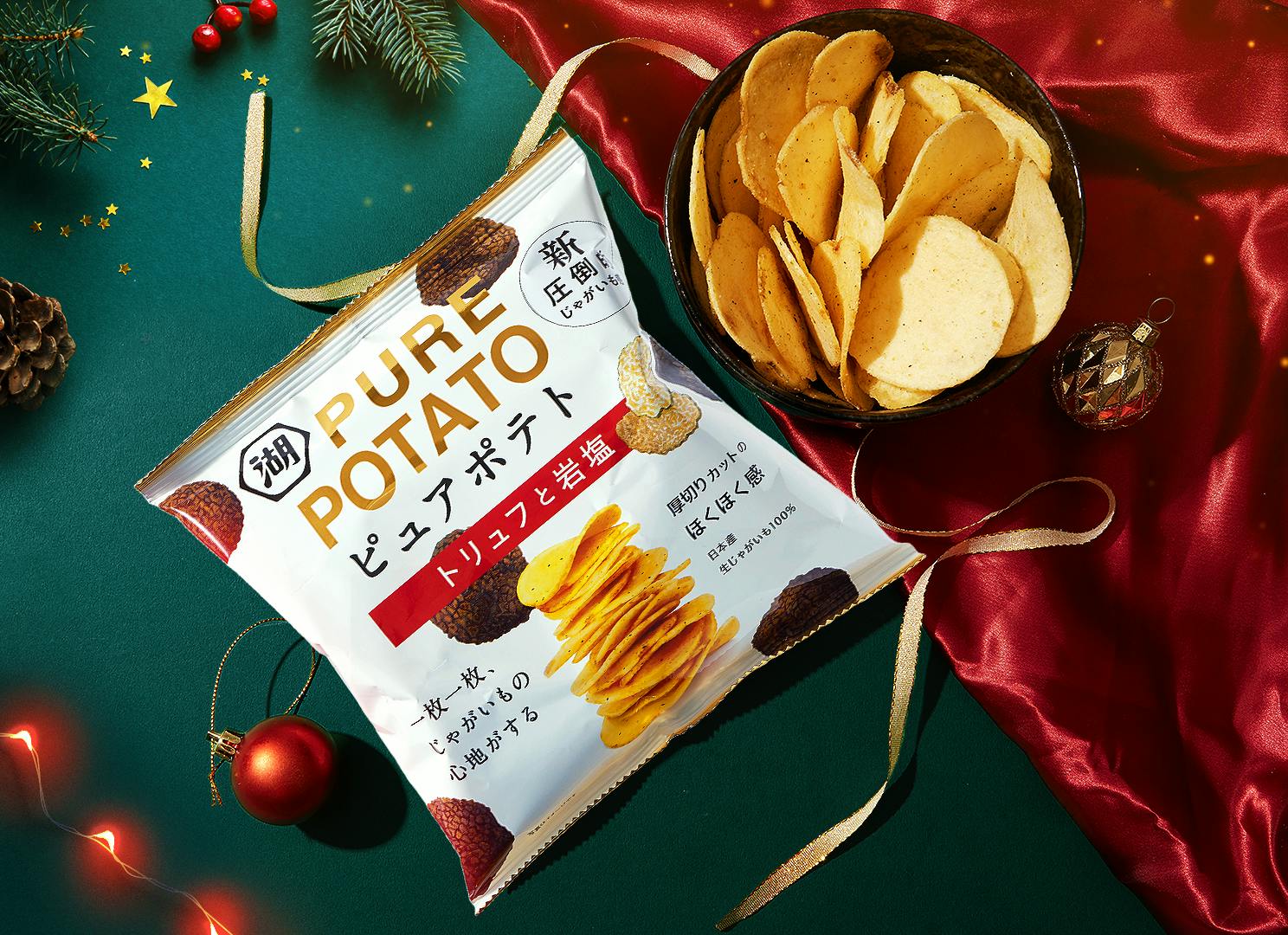 Featured chips from the TokyoTreat December box sit against a backdrop of green & red satin, surrounded by holiday ornaments & other Christmas motifs.