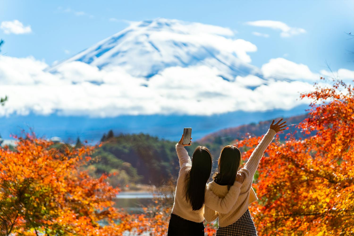 Two friends on a trip in Japan to Mt. Fuji, taking a photo in front of the famous mountain.
