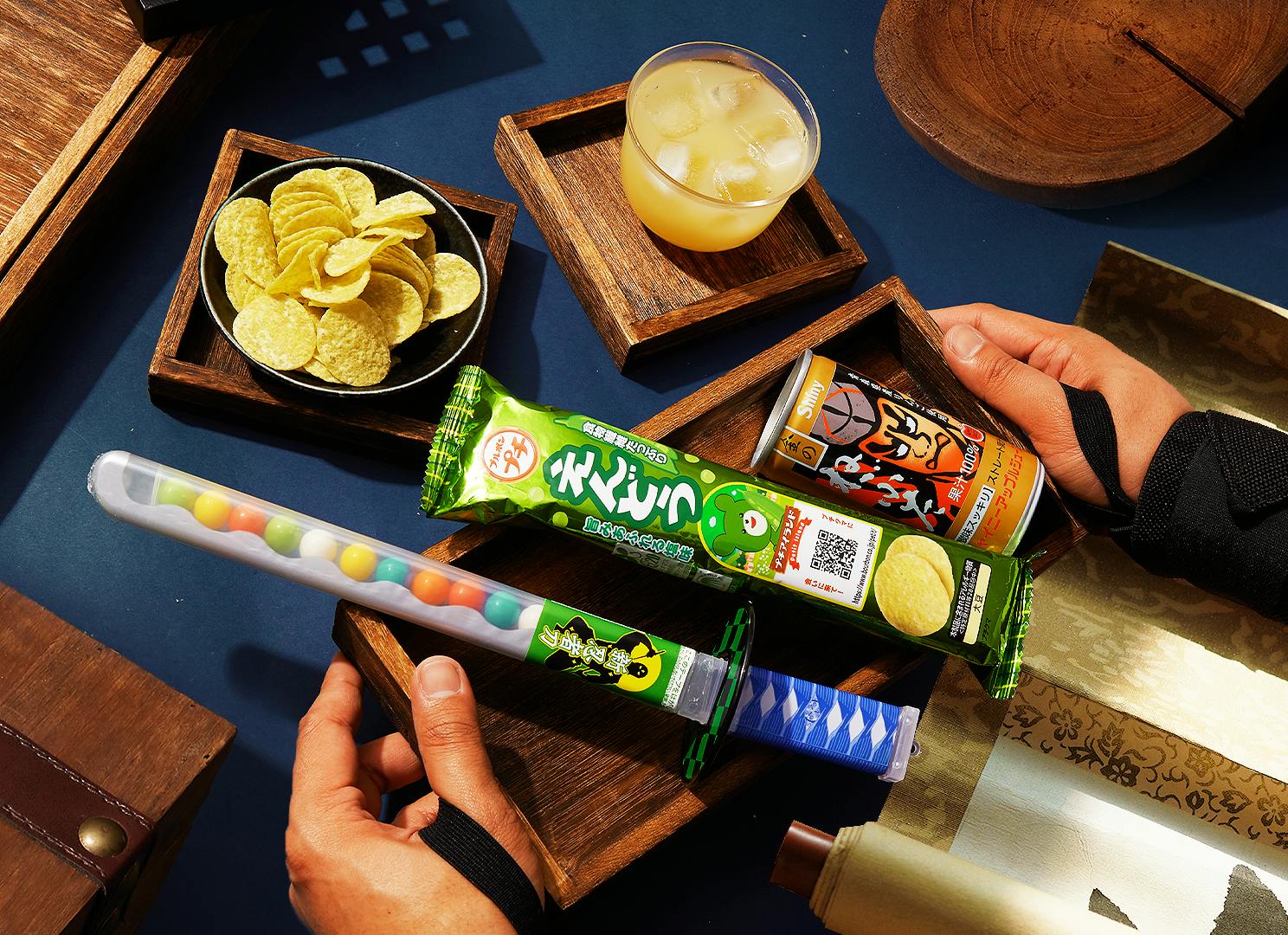 Katana Candy Sword, Endou Pea Chips, and Gold Nebuta Apple Juice sit on a blue and dark wood background, surrounded by ninja motifs.