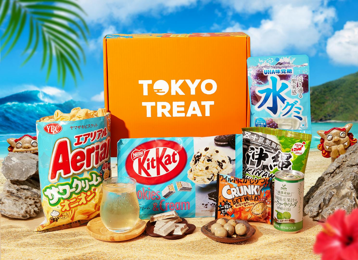 The Okinawa Snackin' Oasis box items sit on an Okinawa beach, surrounded by Okinawa motifs.
