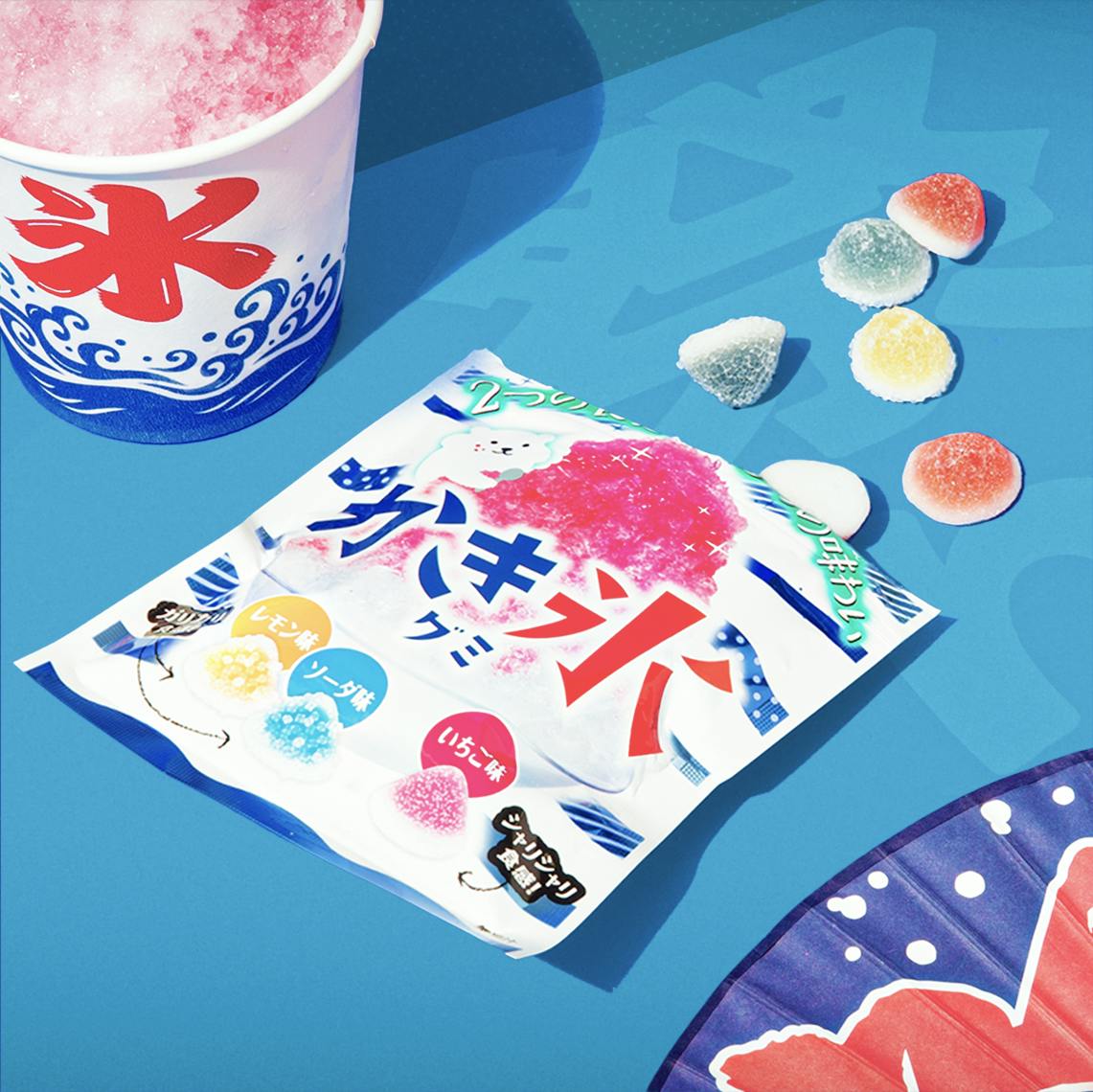Kakigoori Gummies sit on a blue background, surrounded by Japanese summer festival motifs.