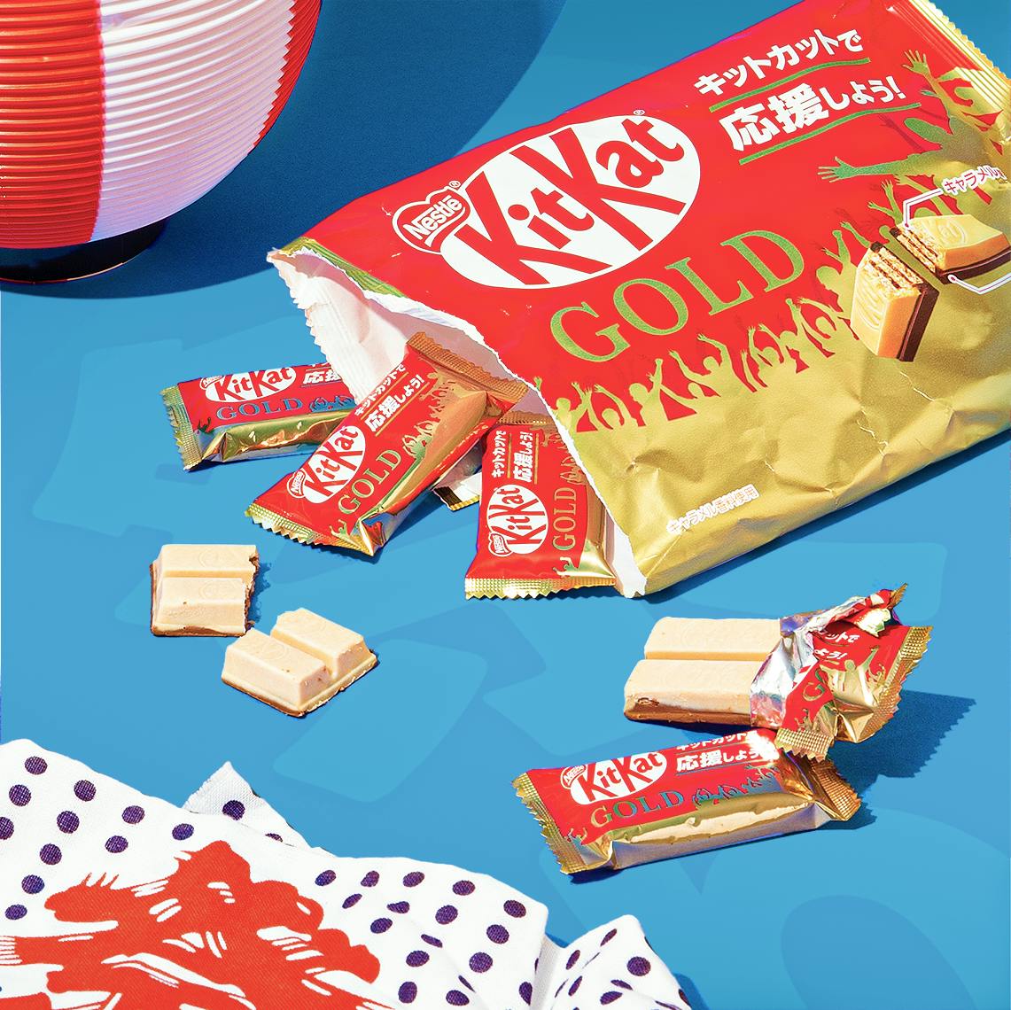 KitKat Gold Caramel sit on a blue background, surrounded by Japanese summer festival motifs.