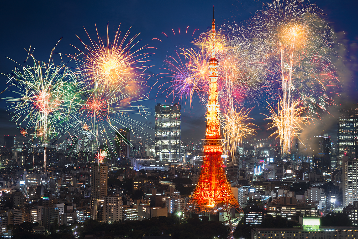 Fireworks light up against a Tokyo skyline, with Tokyo Tower lit up in red.