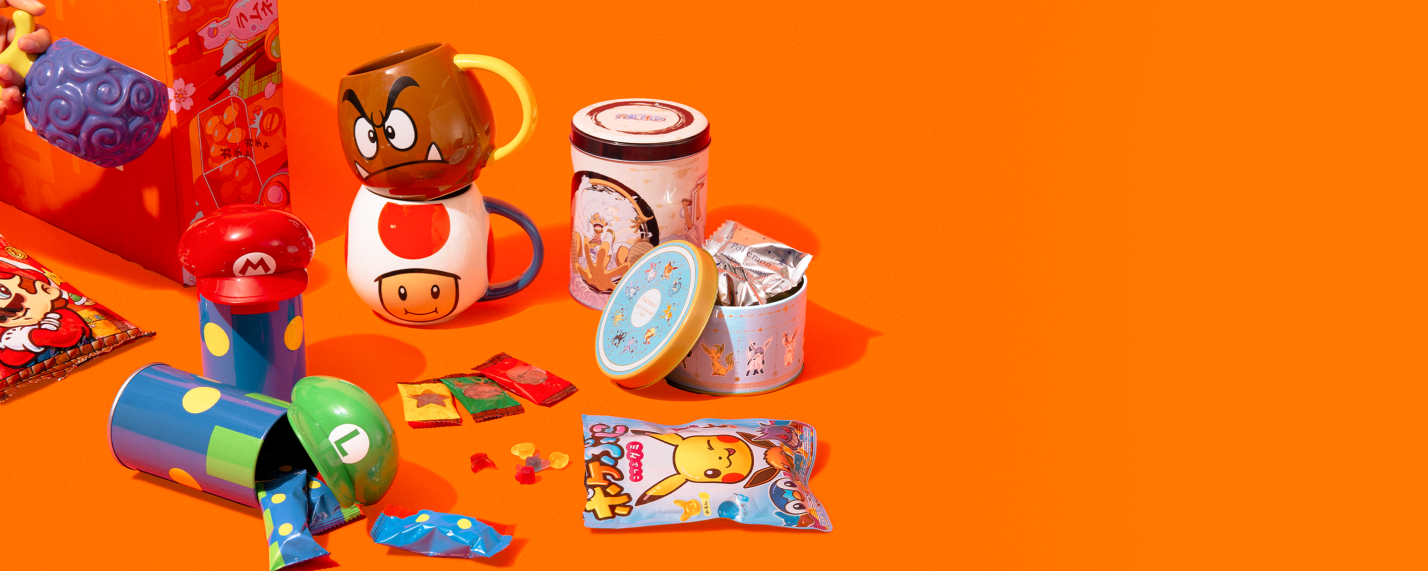 Pokémon, One Piece, and Nintendo mugs, candies, and snack tins on an orange background.