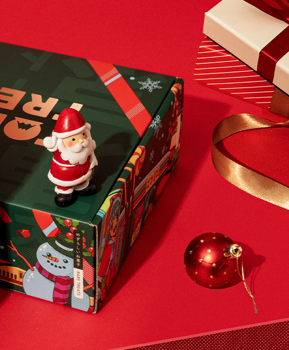 The Very Merry Christmas box next to a Christmas ornament on a red background.