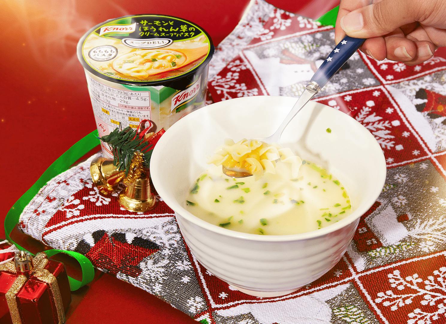 A man dips a spoon into creamy pasta on a Christmas placemat.