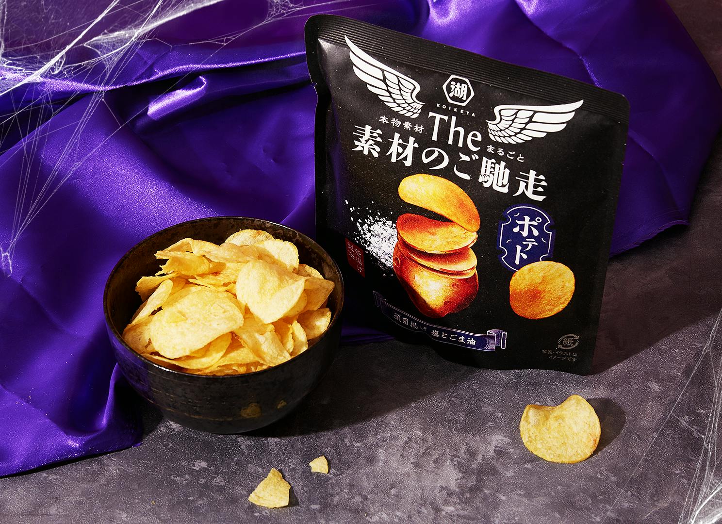 Koikeya Salt & Sesame Oil Potato Chips sit against a velvet purple backdrop with a few Halloween spider webs.