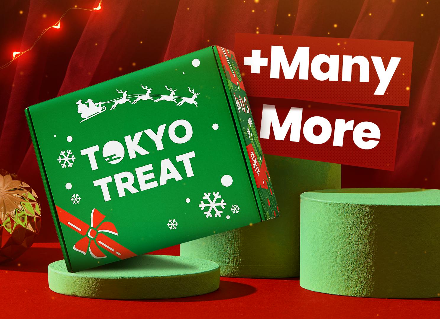 The TokyoTreat special-edition Christmas box sits on a green pedastal, in front of dark red curtains and bright Christmas lights.