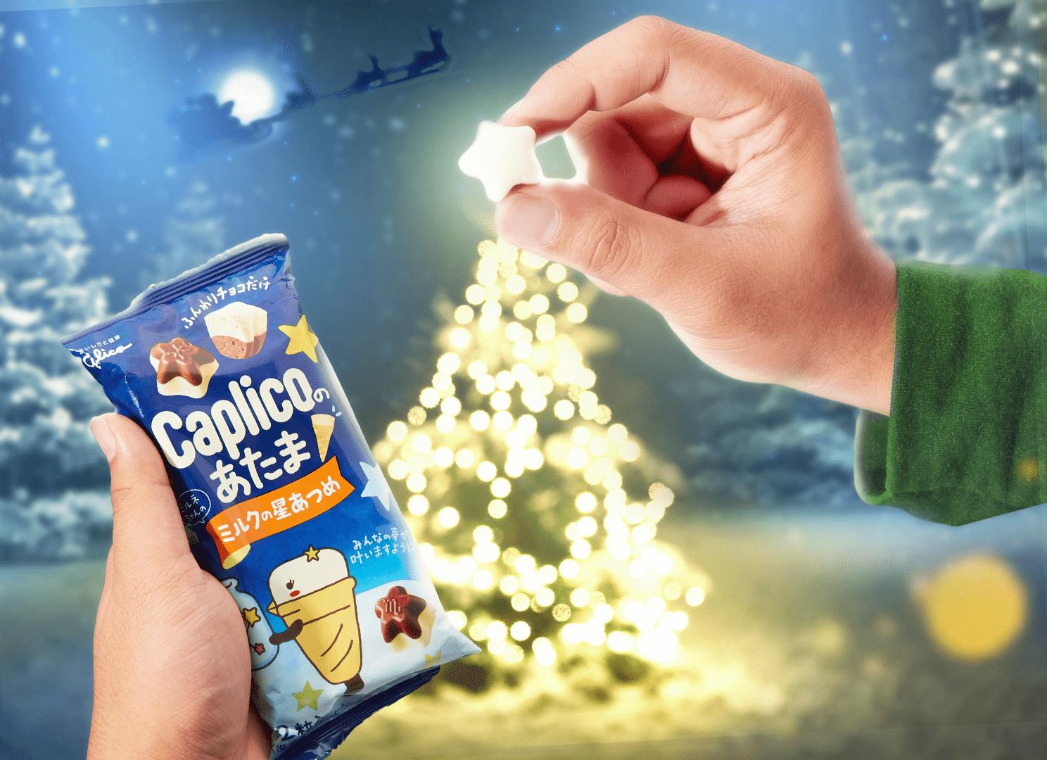 A man holds a star-shaped chocolate candy over a Christmas tree.