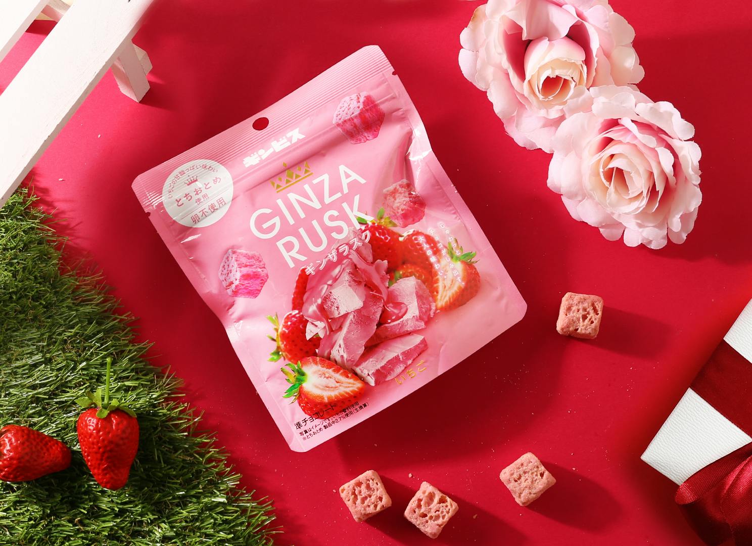Strawberry Ginza Rusk is laid next to pink carnations and fresh strawberries.