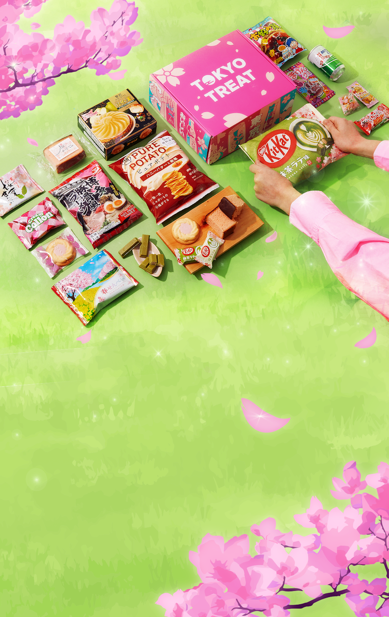 The TokyoTreat special-edition Sakura box sits against a cherry blossom backdrop surrounded by green grass and sakura snack items.