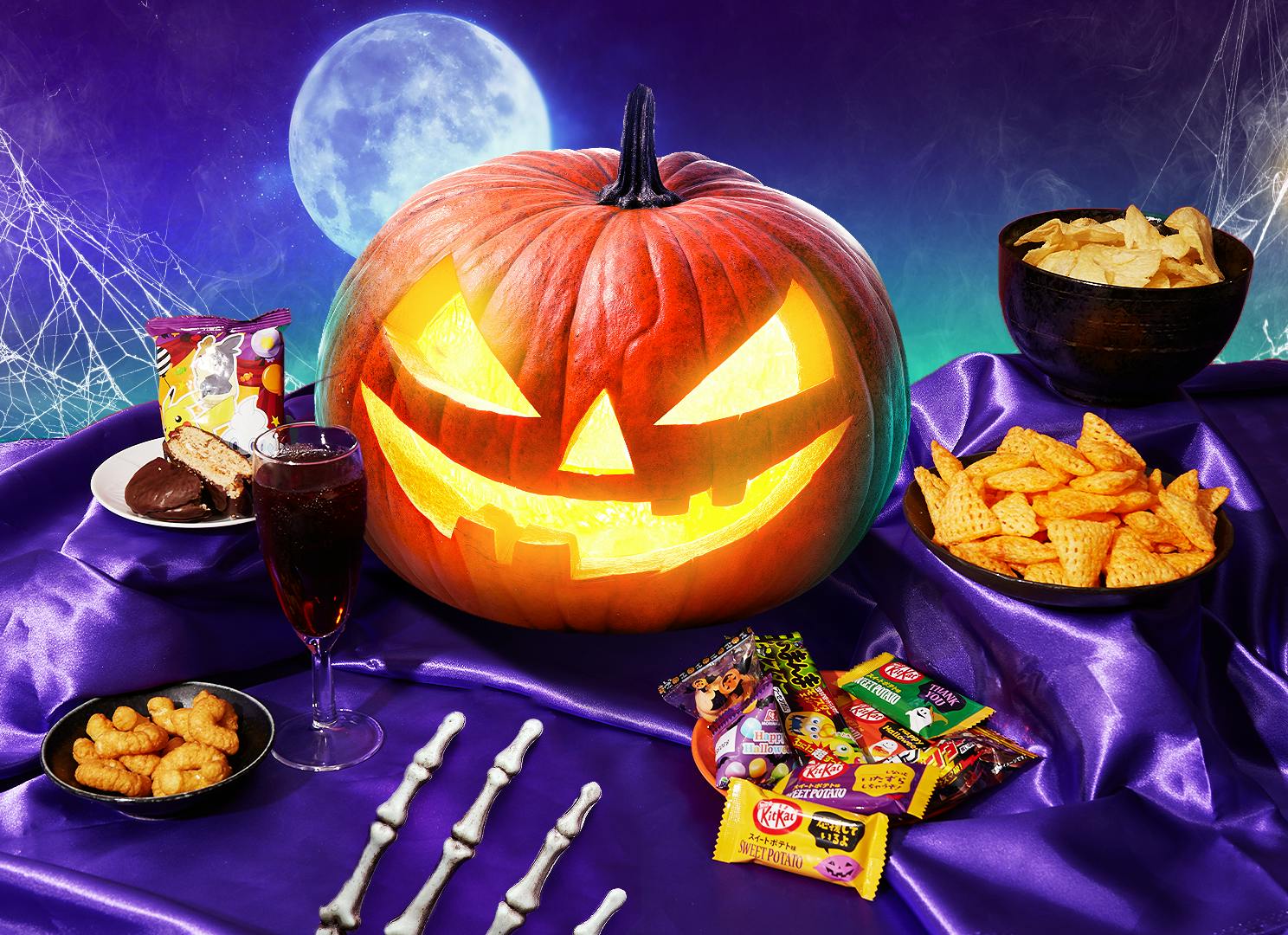 Items from the Halloween SnackHaul box sit on a purple velvet backdrop next to a Jack-o-lantern.