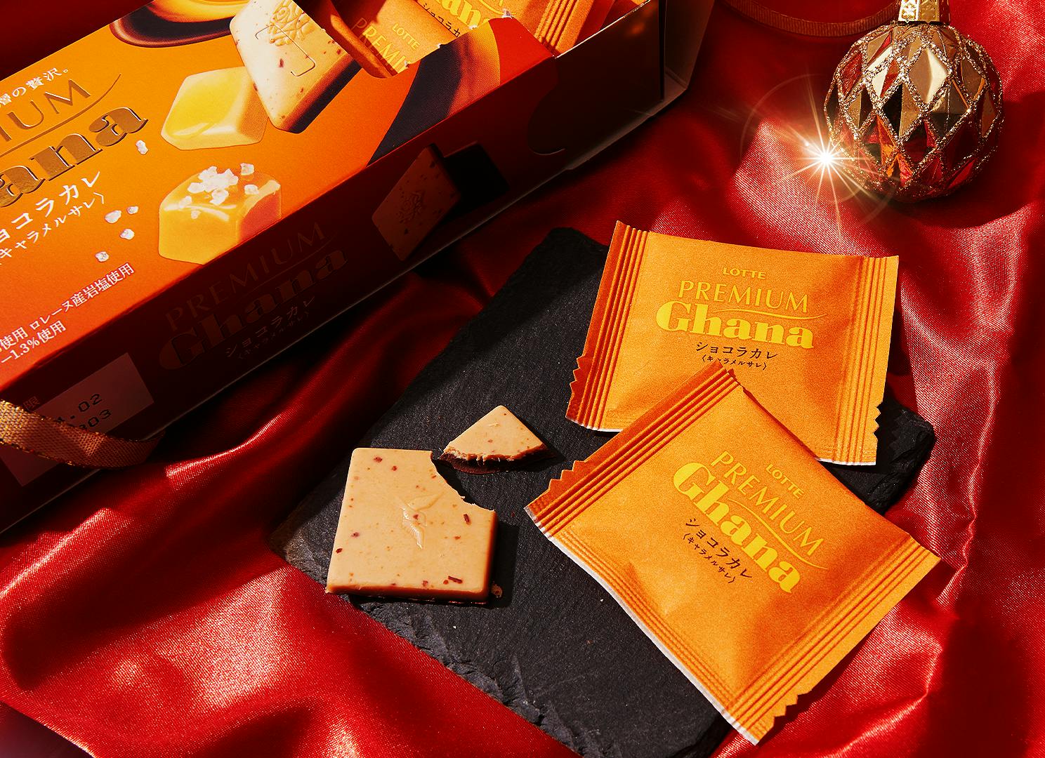 Premium Ghana Chocolate Caramel sit on a red satin background next to Christmas ornaments. Premium Ghana Chocolate Caramel sit on a red satin background next to Christmas ornaments.