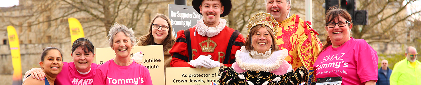 A group of people posing with 3 people in fancy dress.