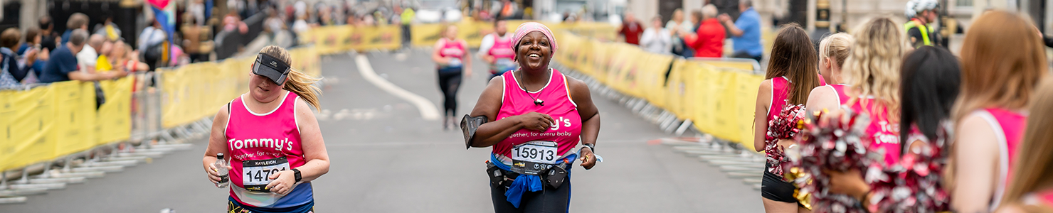 Tommy's runners crossing the LLHM finish line with people cheering at the sides.