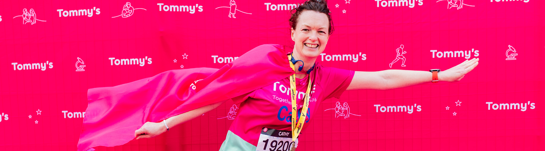 Person posing with a flag on their back wearing their LLHM medal