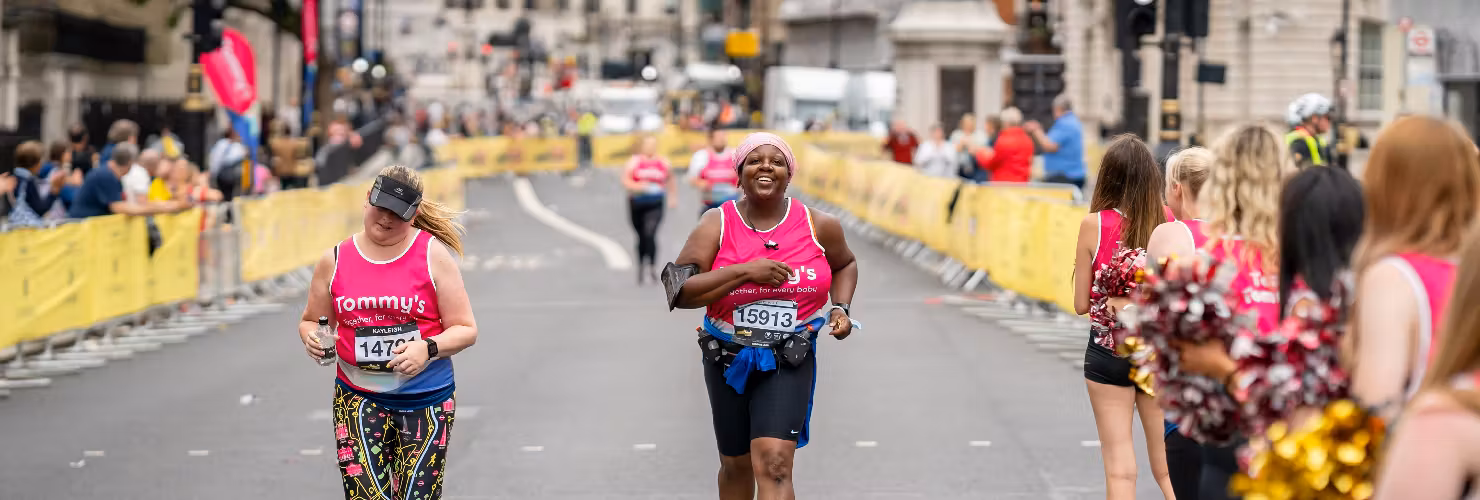 Tommy's runners crossing the LLHM finish line with people cheering at the sides