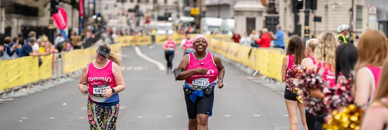 Tommy's runners crossing the LLHM finish line with people cheering at the sides
