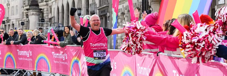 A man running and smiling high fiving supporters