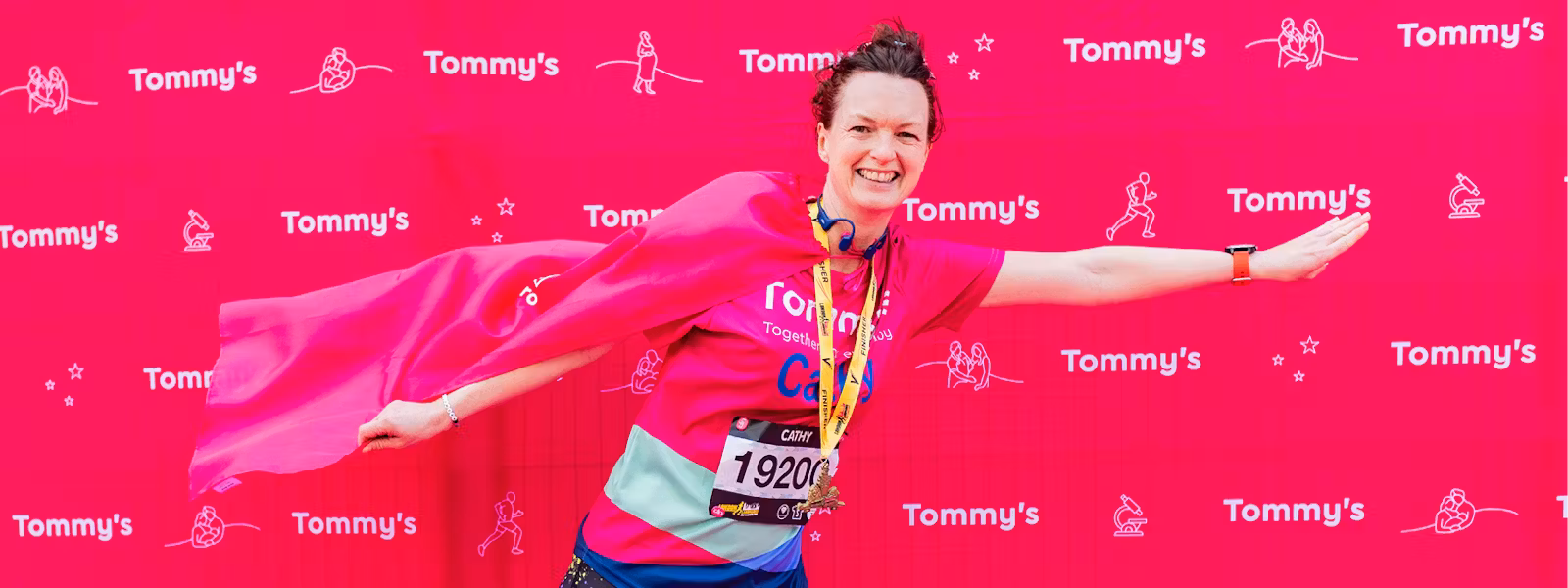 Person posing with a flag on their back wearing their LLHM medal
