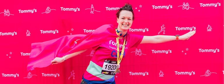 Person posing with a flag on their back wearing their LLHM medal