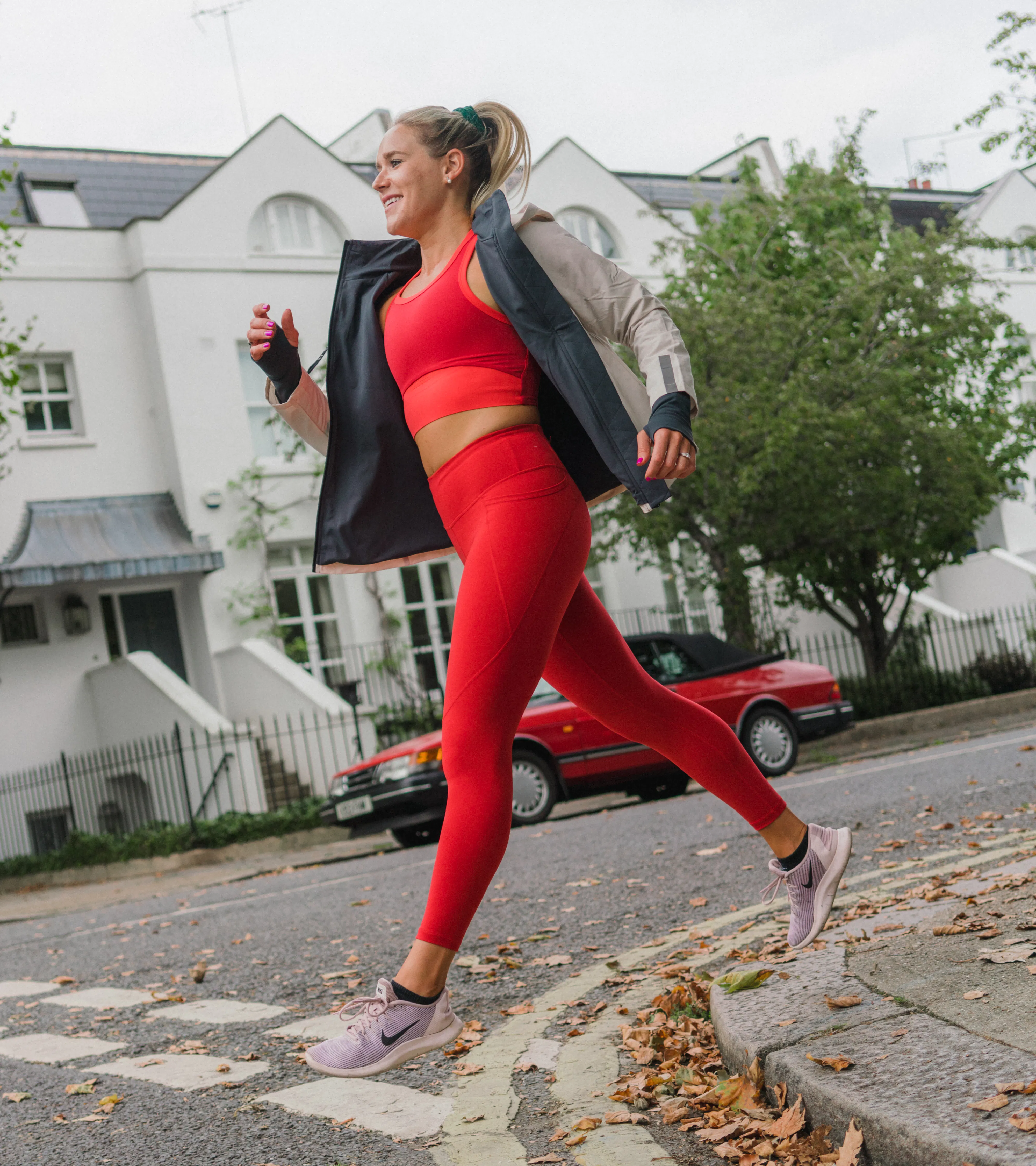 Woman wearing red sportswear running in the street.