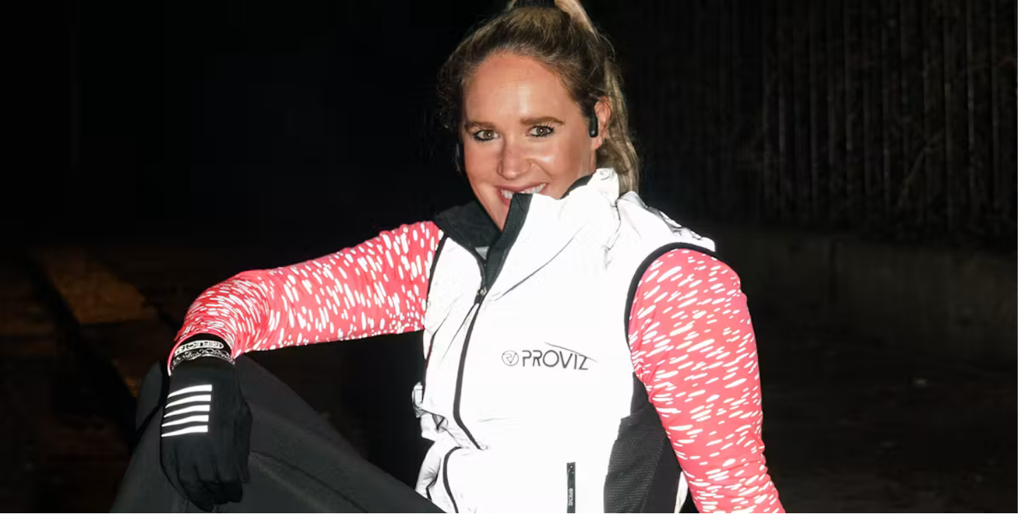 Person wearing a reflective white gilet and red patterned sleeves, posing outdoors at night.