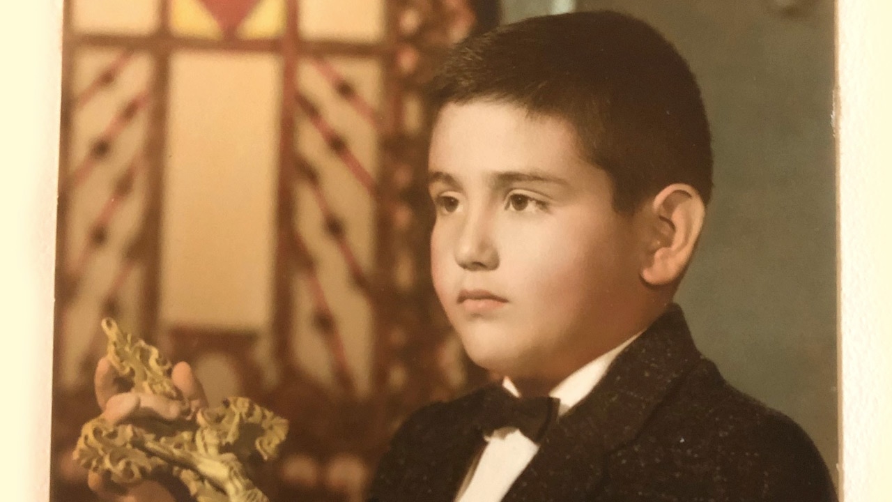 Young Joe Lama in a church holding a crucifix