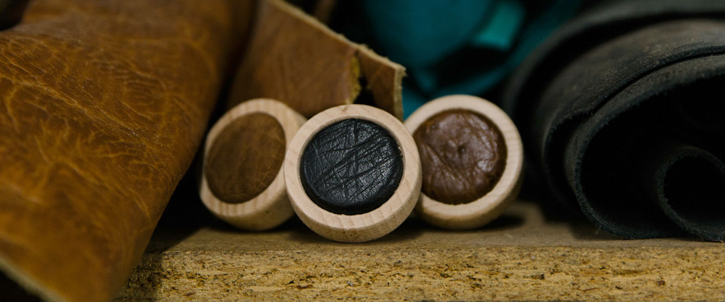 Whiskey bottle caps with leather tops next to rolls of leather.