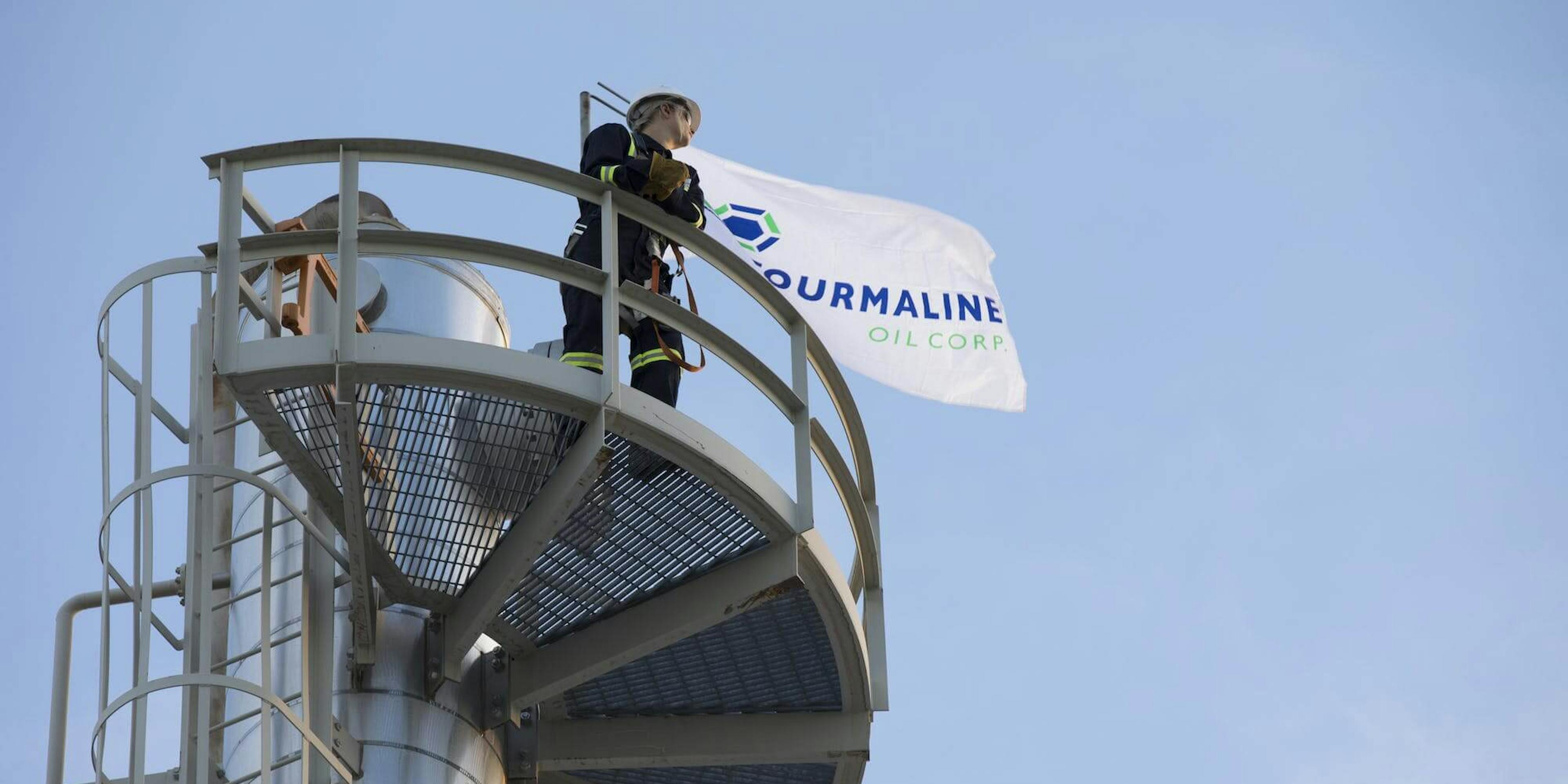 A worker at Tourmaline Oil Corp stands proudly next to the company's flag.