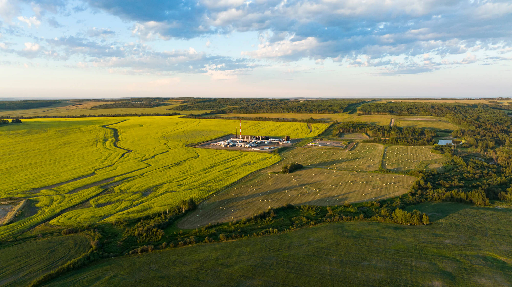 A gas plant in a pristine green field beneath a blue sky.