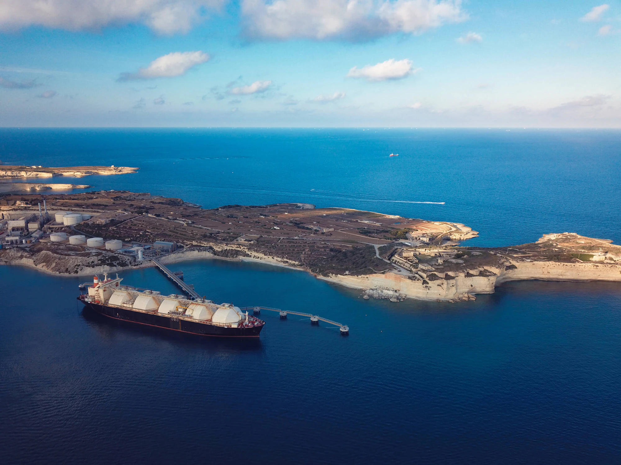A large tanker boat departing from an island facility.