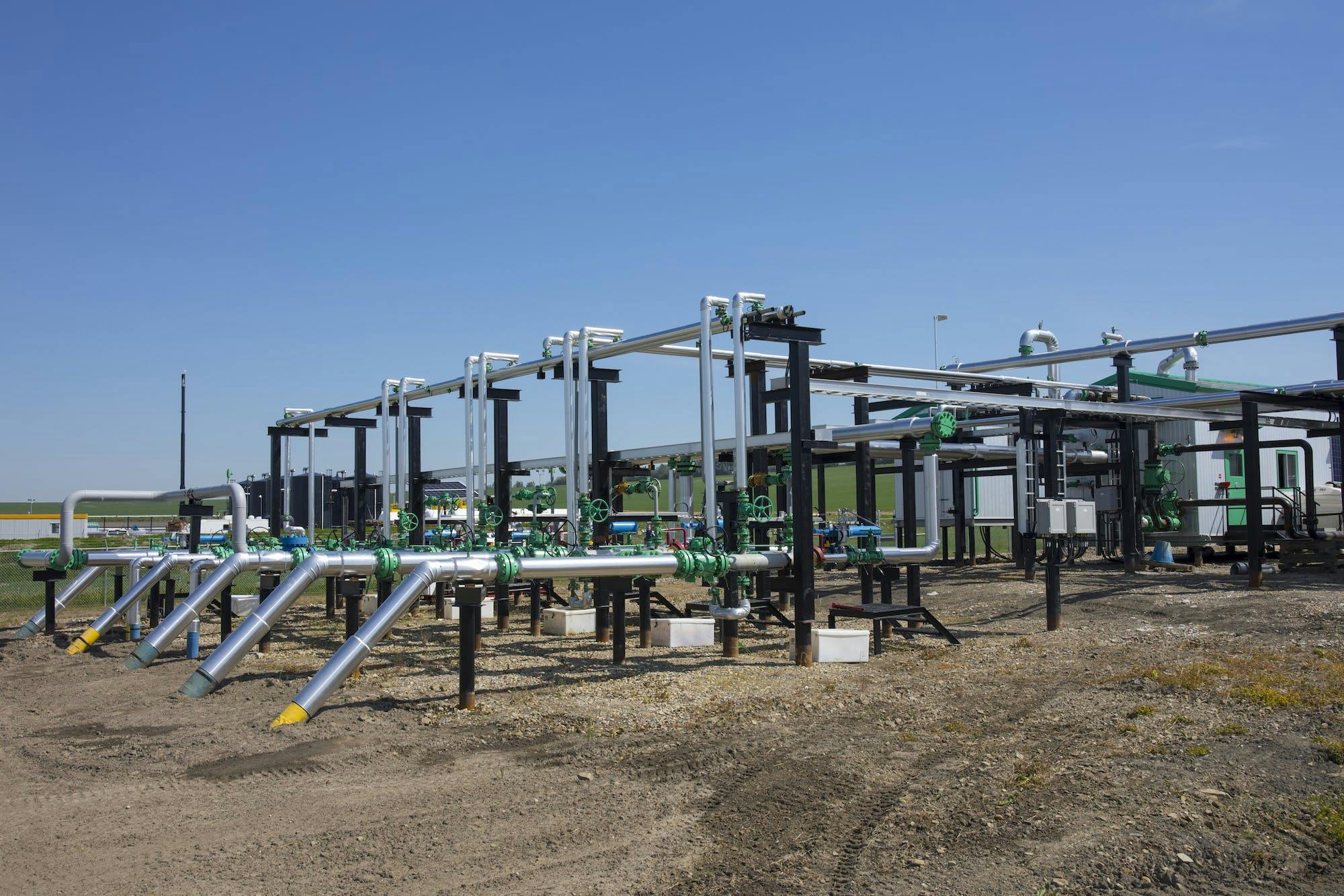 A row of pipes with green connectors, at a gas plant.