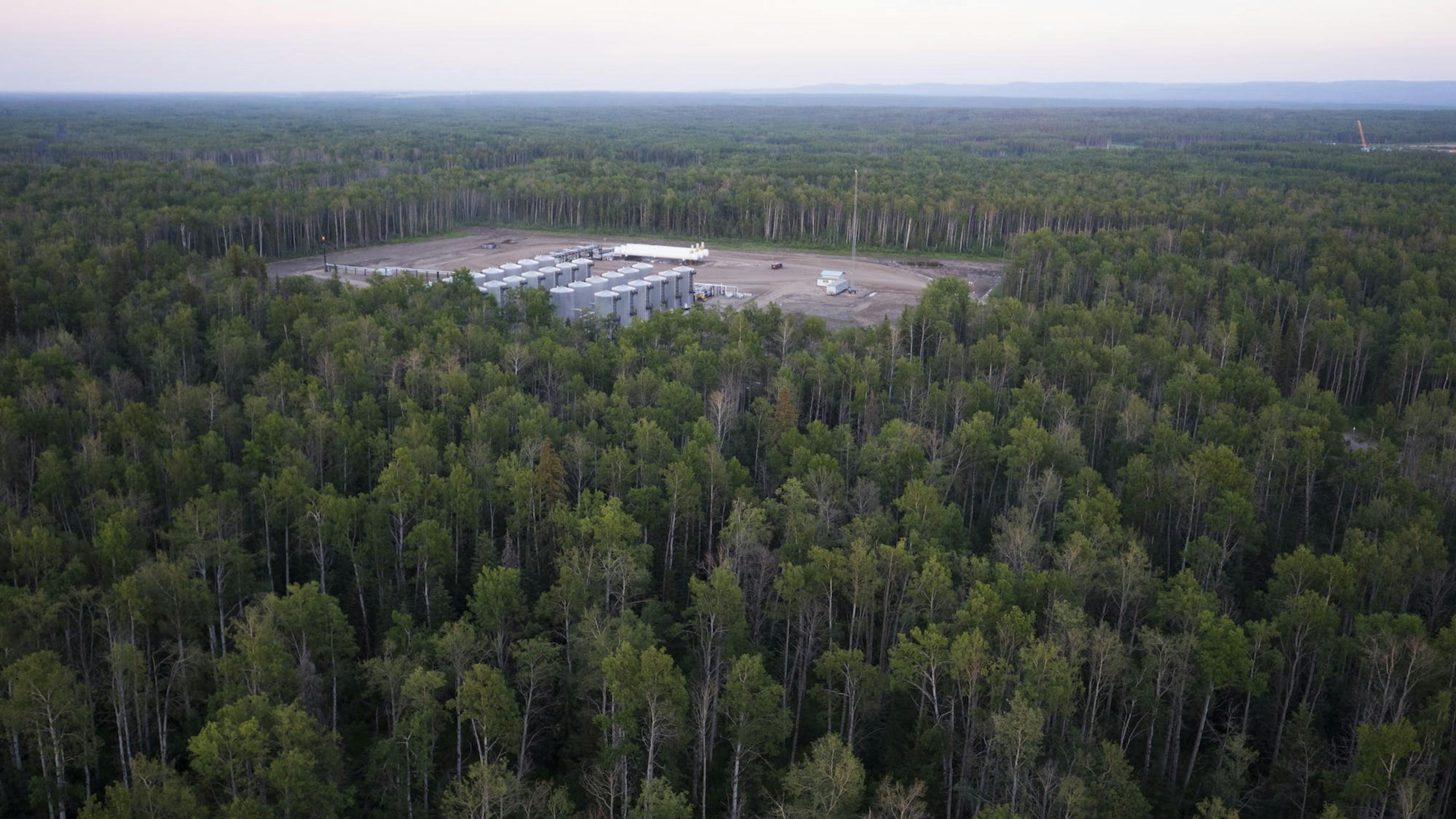 An aerial view of a gas plant in a dense forest.