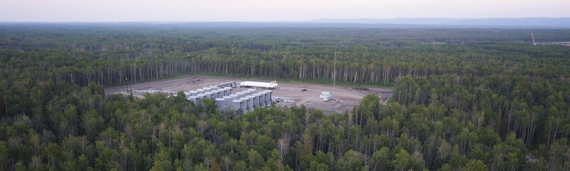 An aerial view of a gas plant in a dense forest.