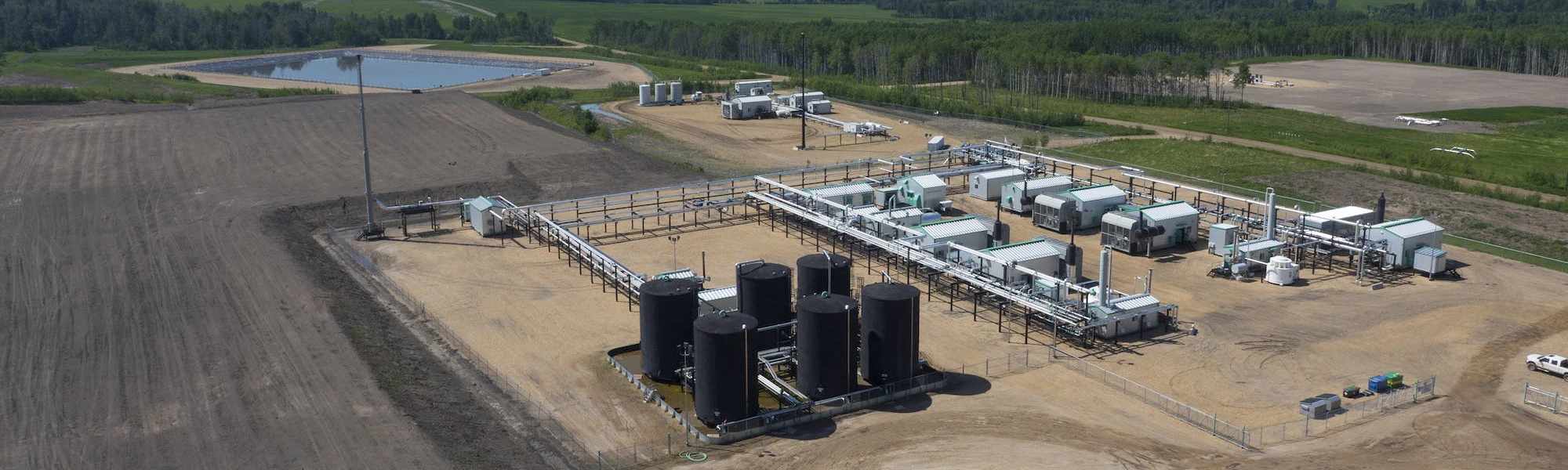 An aerial view of a gas plant, with a small lake in the background.