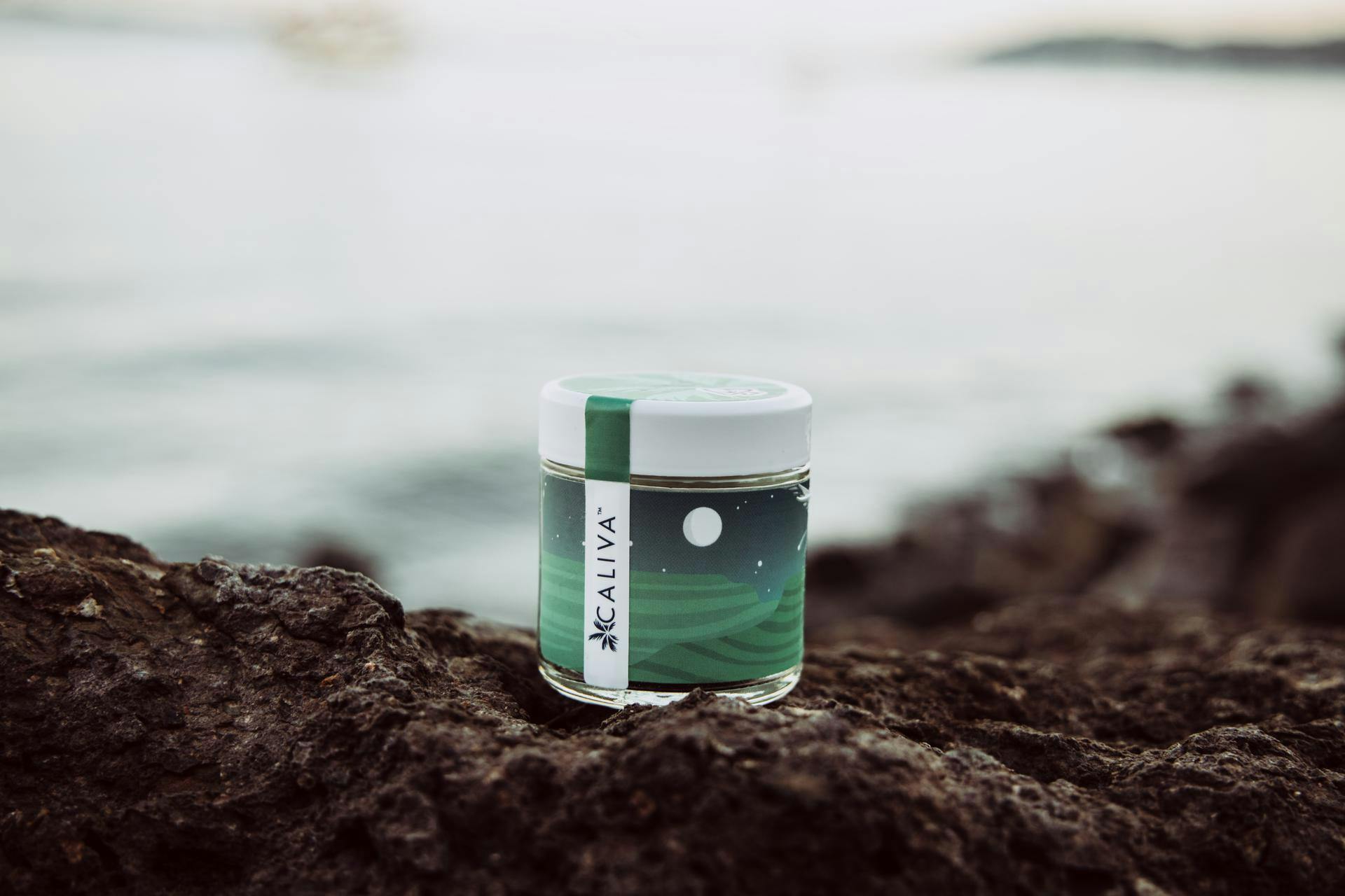 Jar of Caliva Alien OG sitting on a rock cliff overlooking the water