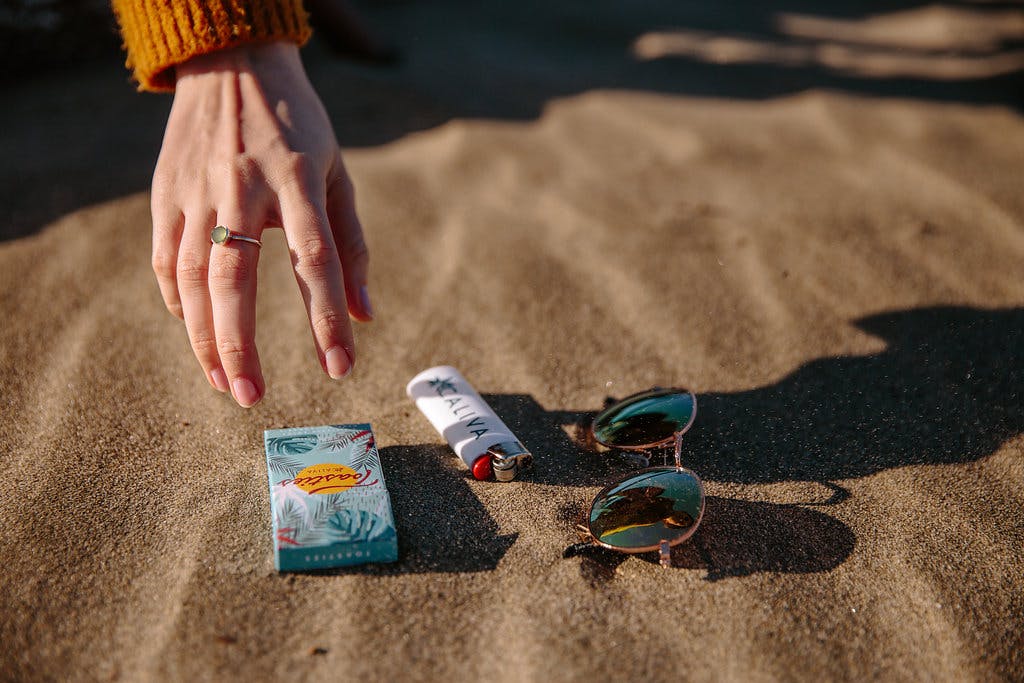 hand reaching for caliva products at the beach 