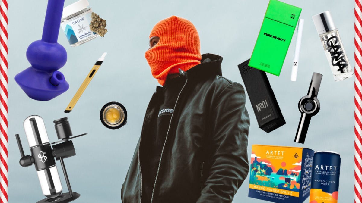 A hypebeast wearing a black leather jacket, hoodie, and an orange balaclava is surrounded by the most luxe gift ideas possible for the holidays. 