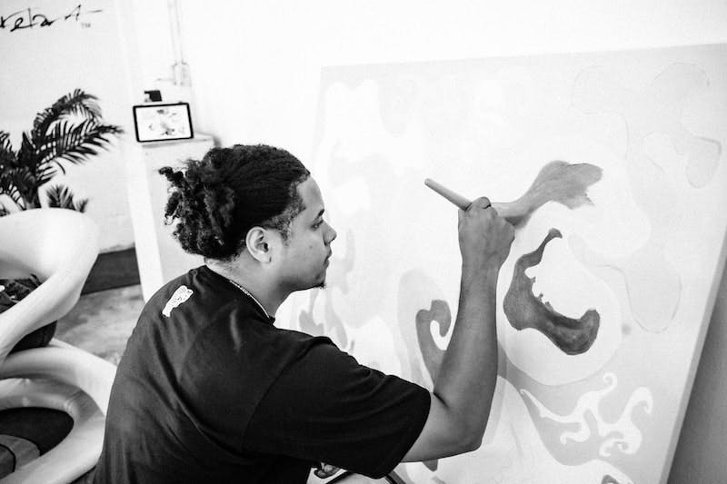 A black and white photograph of an artist painting in his studio. 