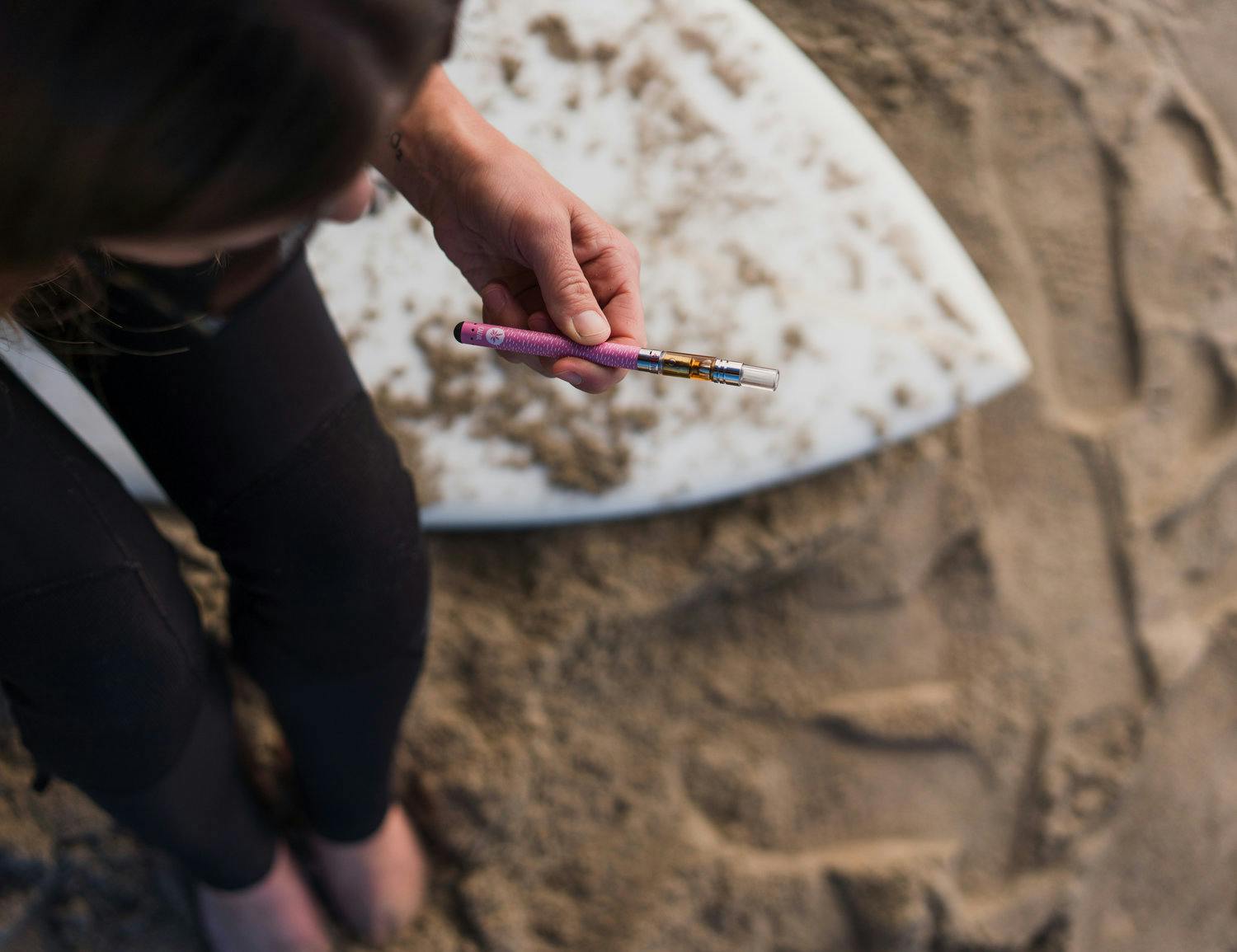 Woman standing on the beach holding a Caliva vape pen.