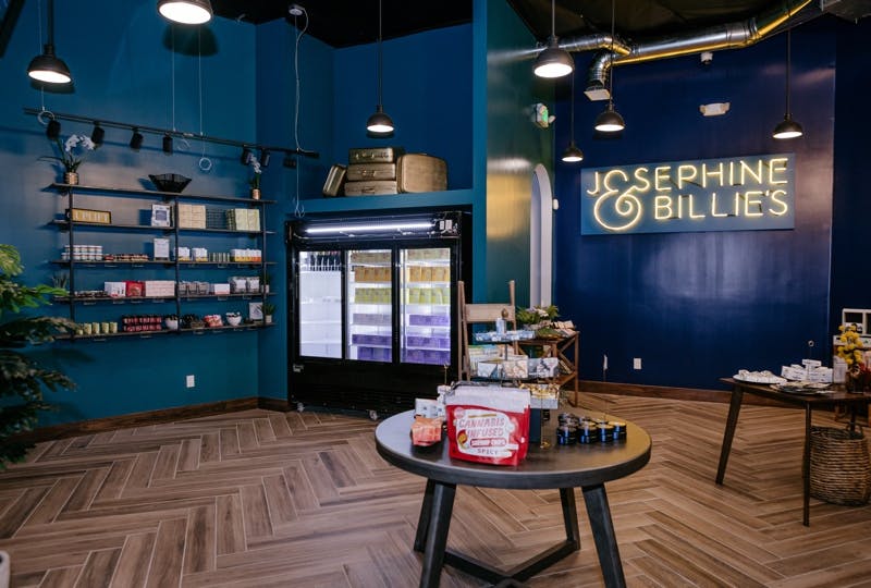 Inside Josephine & Billie's dispensary, with a neon sign displaying the name. 