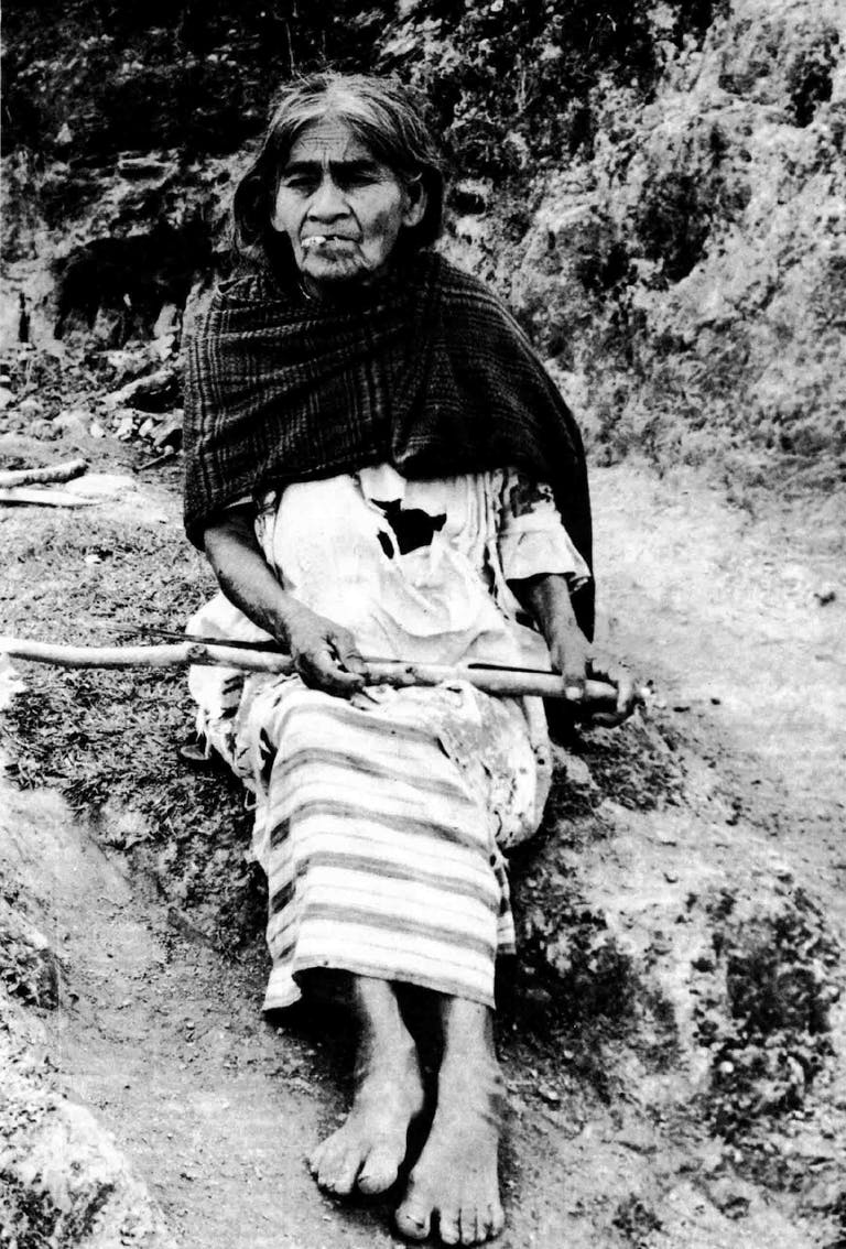 A historical black and white photograph of cuandera Maria Sabina smoking.