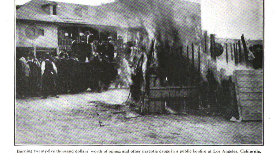 Newspaper clipping photograph of the burning of twenty-five thousand dollars' worth of opium, cannabis, and other narcotic drugs in a public bonfire in Los Angeles, California in 1915. 