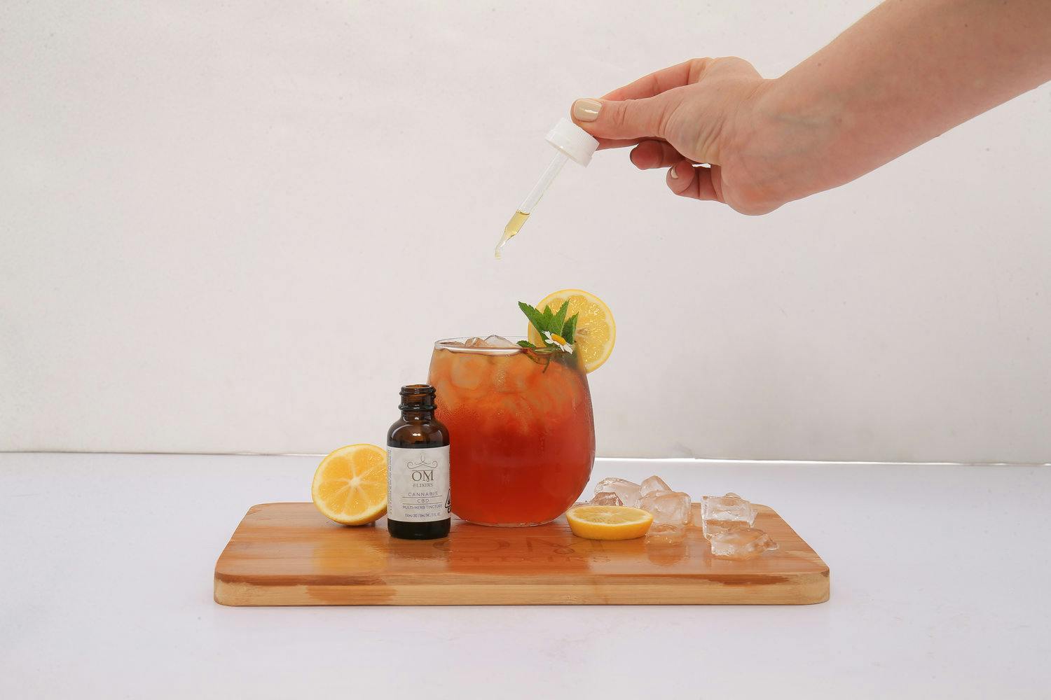 Person using dropper adding CBD tincture to cocktail.