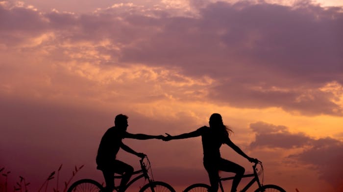 Two people biking during sunset