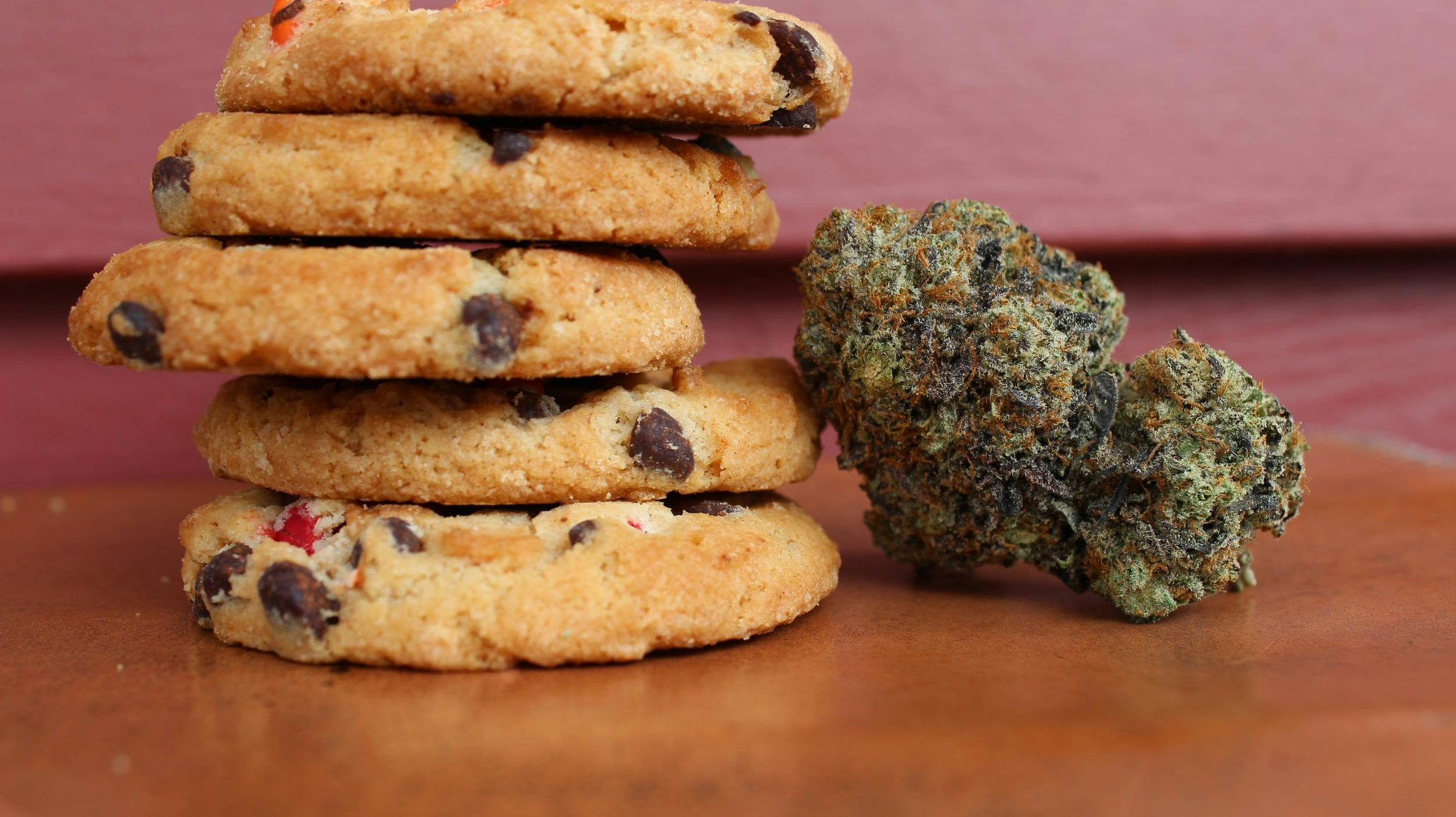 Stack of chocolate chip cookies next to a cannabis nug.
