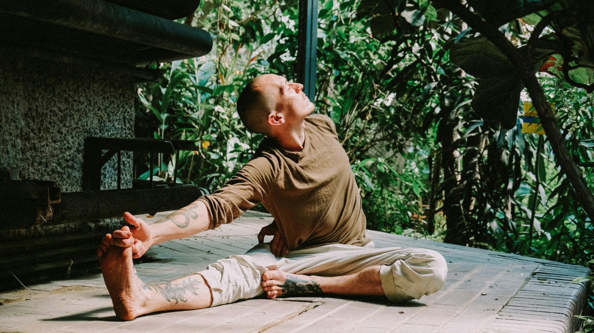 Man stretches while sitting in a meditative state.